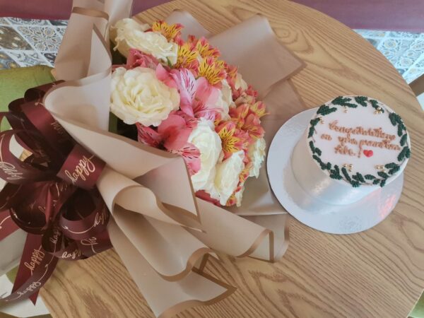 Cake with Congratulations on your promotion Abe! lettering on top and a flower bouquet